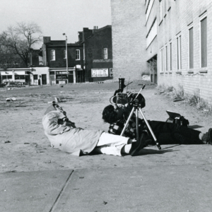 Lawrence Hagan, production assistant, and Steve Carver lying on the ground, shooting footage at Pruitt-Igoe during production of "More Than One Thing"